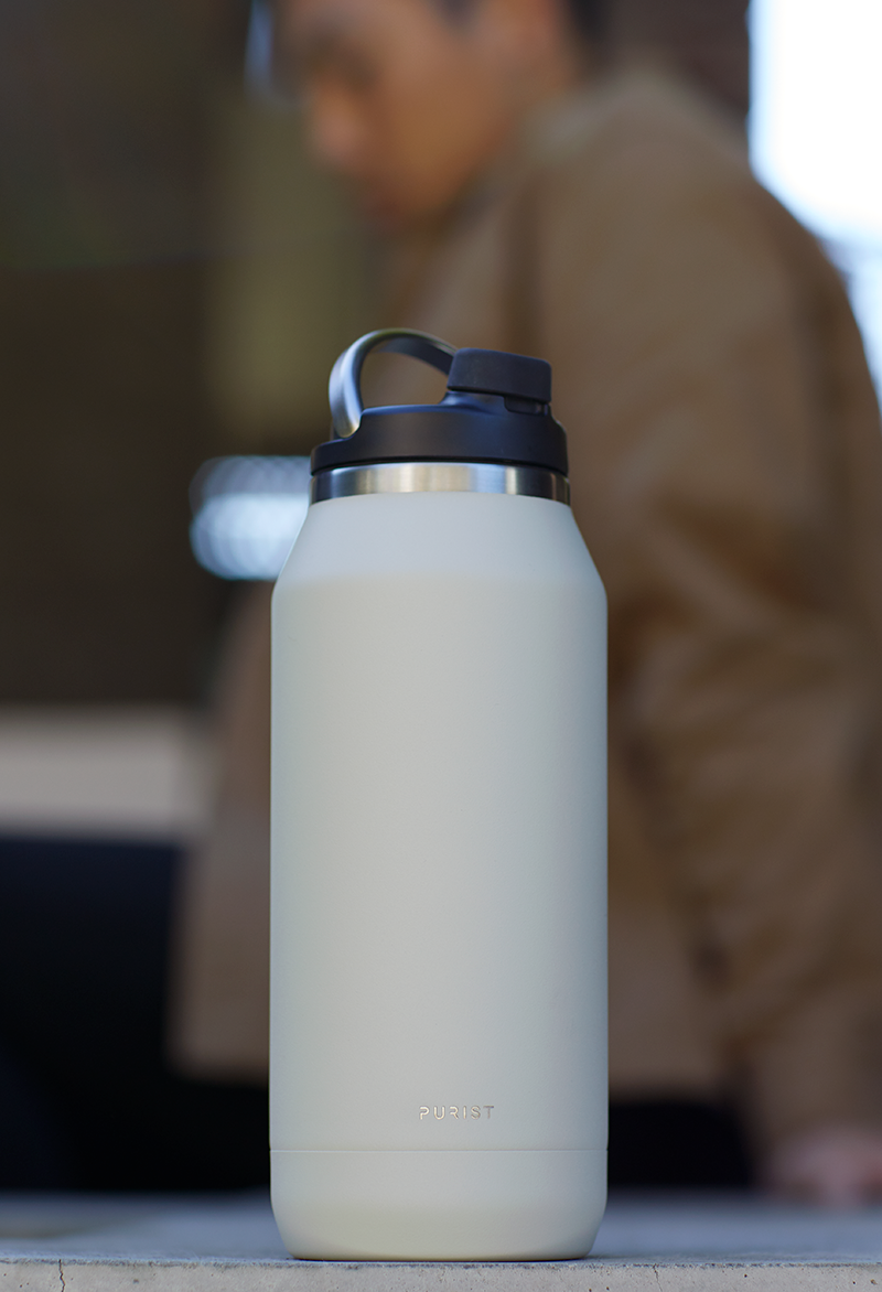 Lifestyle shot of Purist 32 oz glass lined bottle in Bone.