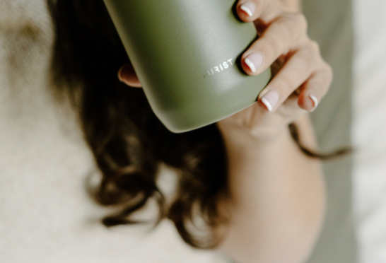Person holding a Purist green insulated mug 