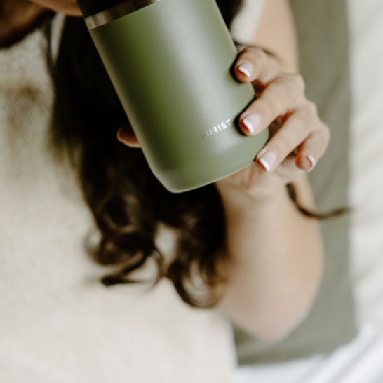 Person holding a Purist green insulated mug 