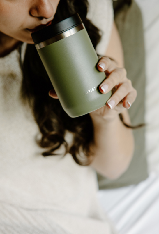 Person holding a Purist green insulated mug 