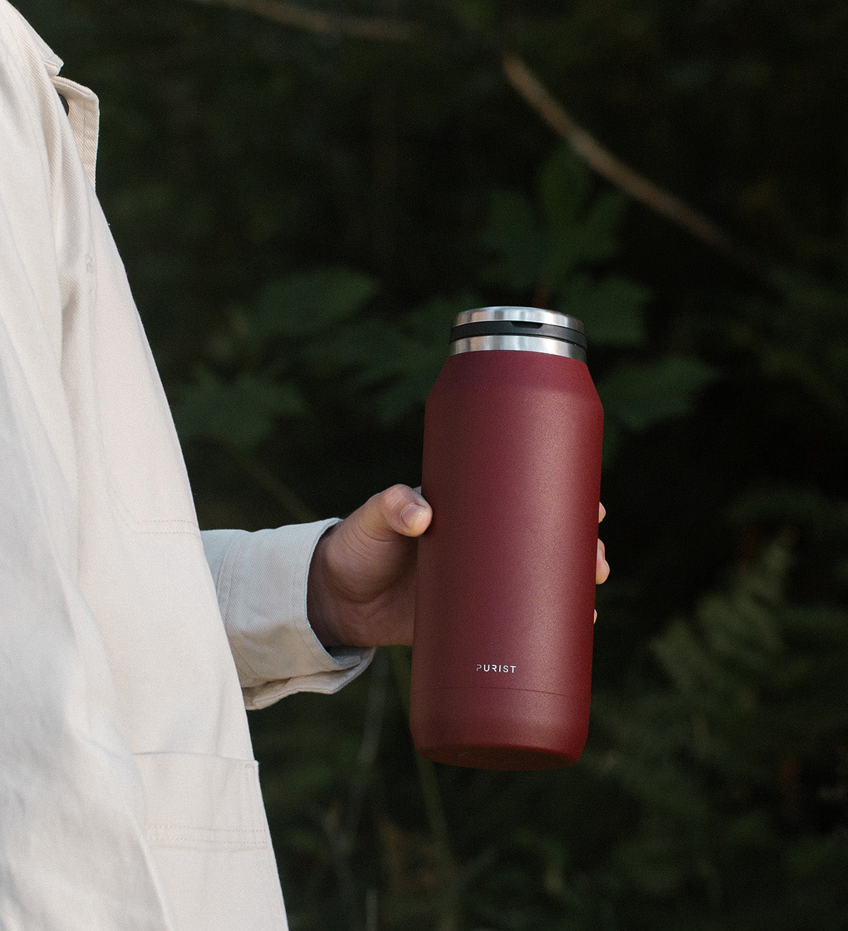 Person holding 32oz Purist glass lined bottle in nature.